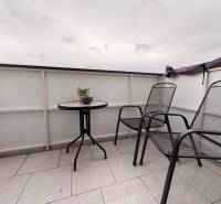 Prenájom moderného 2-izbového bytu v centre Komárna, 40 m² – Petőfiho  - Balkón 2-izbového bytu v Komárne s dvoma stoličkami a stolíkom na dlažbe.