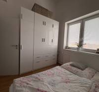 Prenájom moderného 2-izbového bytu v centre Komárna, 40 m² – Petőfiho  - Spálňa v 2-izbovom byte s podlahou s dreveným dekorom a veľkou skriňou.