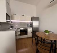 Prenájom moderného 2-izbového bytu v centre Komárna, 40 m² – Petőfiho  - Kuchyňa v 2-izbovom byte s podlahou s dreveným dekorom a jedálenským stolom.