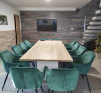 NOVOSTAVBA: 6-izbová CHATA, VL pozemok 484 m2 v Martine  - Jedáleň v chate s dreveným dekorom, schodiskom a zelenými stoličkami okolo stola.