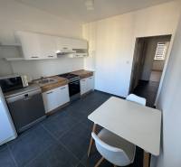 3 izbový zrekonštruovaný byt na prenájom - Martin - Kuchyňa v 3-izbovom byte s bielymi skrinkami a stolom, na tmavej podlahe.