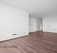 ALL INCLUSIVE I 3 IZBOVÉ BYTY S TERASOU, SO ZÁHRADOU + 2 PARK. MIESTA - Priestranný interiér 3-izbového bytu s podlahou s dreveným dekorom a bielymi stenami.