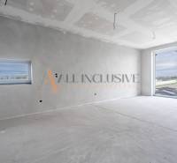 ALL INCLUSIVE I 3 IZBOVÉ BYTY S TERASOU, SO ZÁHRADOU + 2 PARK. MIESTA - Priestranná miestnosť v 3-izbovom byte, s veľkým oknom a bielymi stenami.