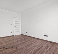 ALL INCLUSIVE I 3 IZBOVÉ BYTY S TERASOU, SO ZÁHRADOU + 2 PARK. MIESTA - Izba v 3-izbovom byte s bielymi stenami a podlahou s dreveným dekorom.