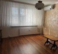 Prenájom 3izb. zariadeného bytu na Jazdeckej ul., Nové Zámky - Izba s podlahou s dreveným dekorom a stolíkom v 3-izbovom byte.