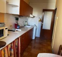 Prenájom 3izb. zariadeného bytu na Jazdeckej ul., Nové Zámky - Kuchyňa v 3-izbovom byte s podlahou s dreveným dekorom, biele skrinky, jedálenský stôl.