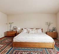 Vidiecky dom v Zemplínskej Teplici - Spálňa v rodinnom dome s posteľou, nočnými stolíkmi a farebným kobercom.