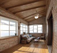 Vidiecky dom v Zemplínskej Teplici - Interiér rodinného domu s tehlovými stenami, podlahou s dreveným dekorom a pohodlným sedením.