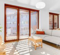 NOVÝ krásny 2i byt, ZWIRN, 2x balkón, parkovanie, Košická - Svetlý obývací priestor s podlahou s dreveným dekorom, gaučom a veľkými oknami v 2-izbovom byte.