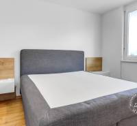 Krásny 3i byt, LODŽIA, PARKING, Dúbravka, Cabanova - Spálňa v 3-izbovom byte s posteľou, dreveným dekorom a vstavanými skrinkami.