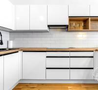 Krásny 3i byt, LODŽIA, PARKING, Dúbravka, Cabanova - Kuchyňa s bielymi skrinkami, čiernym drezom a podlahou s dreveným dekorom v 3-izbovom byte.