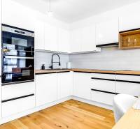 Krásny 3i byt, LODŽIA, PARKING, Dúbravka, Cabanova - Kuchyňa v 3-izbovom byte s bielymi skrinkami a podlahou s dreveným dekorom.