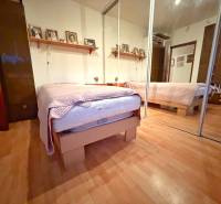 - PREDAJ - 3 izbový byt - Estónska ul. - Vrakuňa  - Spálňa v 3-izbovom byte s posteľou, zrkadlovou skriňou a podlahou s dreveným dekorom.