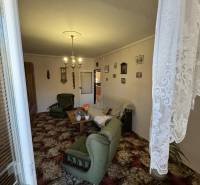 Šahy – 3i Byt v Centre Mesta s Balkónom  - Obývacia izba v 3-izbovom byte so zeleným nábytkom a dekoratívnym kobercom.