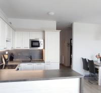 | 2-izbový byt, ul. Predmerského VINOHRADY | Trenčín  - Kuchyňa 2-izbového bytu s bielymi skrinkami a jedálenským stolom, podlaha s dreveným dekorom.