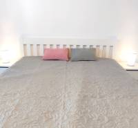 | 2-izbový byt, ul. Predmerského VINOHRADY | Trenčín  - Spálňa s posteľou, dvoma vankúšmi a nočnými stolíkmi v 2-izbovom byte.