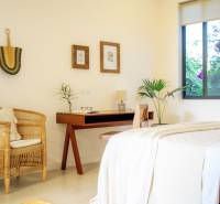 LUXURY 2-BEDROOM VILLA IN PAJE - Svetlá spálňa v rodinnom dome s ratanovým kreslom a dreveným stolom.