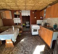 Predáme záhradu s možnosťou výstavby na Strednej ulici v Ružinove - Kuchyňa so starším nábytkom, podlaha s dreveným dekorom, viditeľná jedálenská časť.