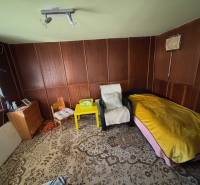 Predáme záhradu s možnosťou výstavby na Strednej ulici v Ružinove - Izba so stoličkami, lôžkom, skrinkou a dekoratívnym kobercom v Záhradách.