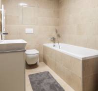 PRENÁJOM - 1 izbový byt v projekte Ovocné sady - Kúpeľňa v 1-izbovom byte s vaňou, práčkou a toaletou v neutrálnych tónoch.