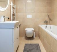 PRENÁJOM - 1 izbový byt v projekte Ovocné sady - Kúpeľňa ladená do béžovej s vaňou, umývadlom a zrkadlom v 1-izbovom byte.