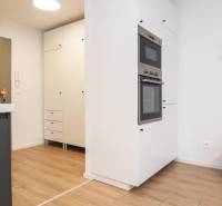 PRENÁJOM - 1 izbový byt v projekte Ovocné sady - Kuchyňa v 1-izbovom byte s bielymi skrinkami a podlahou s dreveným dekorom.