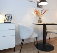 PRENÁJOM - 1 izbový byt v projekte Ovocné sady - 1-izbový byt s dekoratívnymi stoličkami, stolom a lampou na podlahe s dreveným dekorom.