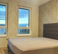 Na prenájom novostavba 2i bytu s parkingom, PRÚDY I., Trnava - Spálňa s veľkým oknom a posteľou v 2-izbovom byte, podlaha s dreveným dekorom.