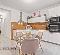 NA PREDAJ 3-IZB. BYT S TERASOU A ZÁHRADKOU, DUN.STREDA - Kuchyňa v 3-izbovom byte s bielymi skrinkami, podlahou s dreveným dekorom a jedálenským stolom.