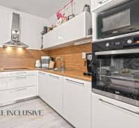 NA PREDAJ 3-IZB. BYT S TERASOU A ZÁHRADKOU, DUN.STREDA - Moderná kuchyňa v 3-izbovom byte s bielymi skrinkami a podlahou s dreveným dekorom.