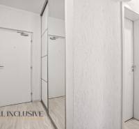 NA PREDAJ 3-IZB. BYT S TERASOU A ZÁHRADKOU, DUN.STREDA - Biele interiérové dvere a zrkadlová skriňa v 3-izbovom byte s podlahou s dreveným dekorom.