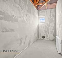 NA PREDAJ 4-IZBOVÝ RD - NOVOSTAVBA, DUNAJSKÁ STREDA  - Nedokončená miestnosť, na stenách sivá omietka, s malým oknom a viditeľnou strešnou konštrukciou.