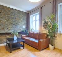 PRIESTRANNÝ 2.IZB. BYT - PIVNICA, LODŽIA - DOBROVSKÉHO, STARÉ MESTO - Obývacia izba v 2-izbovom byte s podlahou s dreveným dekorom a tehlovým obkladom.