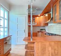 PRIESTRANNÝ 2.IZB. BYT - PIVNICA, LODŽIA - DOBROVSKÉHO, STARÉ MESTO - Kuchyňa v 2-izbovom byte s drevenými skrinkami a podlahou s dreveným dekorom.