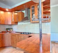 PRIESTRANNÝ 2.IZB. BYT - PIVNICA, LODŽIA - DOBROVSKÉHO, STARÉ MESTO - Kuchyňa v 2-izbovom byte s drevenými skrinkami a podlahou s dreveným dekorom.