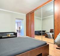 PRIESTRANNÝ 2.IZB. BYT - PIVNICA, LODŽIA - DOBROVSKÉHO, STARÉ MESTO - Spálňa v 2-izbovom byte s veľkou skriňou a podlahou s dreveným dekorom.