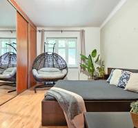 PRIESTRANNÝ 2.IZB. BYT - PIVNICA, LODŽIA - DOBROVSKÉHO, STARÉ MESTO - Spálňa v 2-izbovom byte s podlahou s dreveným dekorom, zrkadlovou skriňou a hojdacím kreslom.