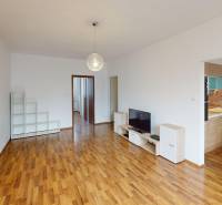 3-izbový byt prerobený na 4-izbový – Ku Bratke, Levice  - Svetlá obývacia izba v 3-izbovom byte s podlahou s dreveným dekorom a kuchyňou.