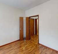 3-izbový byt prerobený na 4-izbový – Ku Bratke, Levice  - Izba v 3-izbovom byte s podlahou s dreveným dekorom a dverami.