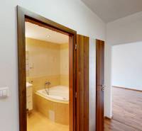 3-izbový byt prerobený na 4-izbový – Ku Bratke, Levice  - Kúpeľňa s vaňou a vedľajšia miestnosť s podlahou s dreveným dekorom v 3-izbovom byte.