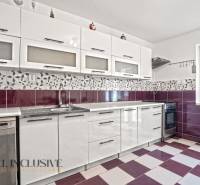 NA PREDAJ 4+1-IZBOVÝ ROD. DOM, VEĽKÉ KOSIHY - Kuchyňa v rodinnom dome s bielymi skrinkami, fialovými dlaždicami a vstavanými spotrebičmi.