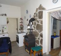 Rodinný dom, chalupa 2 Izbový - Fony - Kuchyňa v rodinnom dome so sporákom, pecou a kamenným obkladom pri stene.