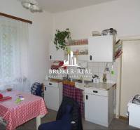 Rodinný dom, chalupa 2 Izbový - Fony - Kuchyňa v rodinnom dome s klasickým zariadením, záclony, biely kuchynský nábytok.