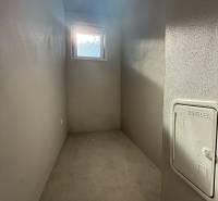 PREDAJ - NOVOSTAVBA - TESÁRSKE MLYŇANY - Úzka úložná miestnosť v rodinnom dome s oknom a betónovou podlahou.