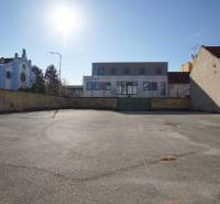 Na predaj jedinečný pozemok priamo v centre, Nové Zámky, 534m² - Asfaltová plocha pred budovami v Nových Zámkoch, ideálne pre Pozemky - bývanie.