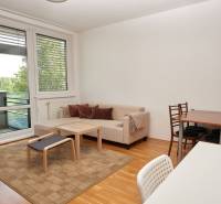 Ponúka prenájom 2 izb. byt na ul. Záporožská na začiatku - Obývacia izba s pohovkou, jedálenským stolom a podlahou s dreveným dekorom v 2-izbovom byte.