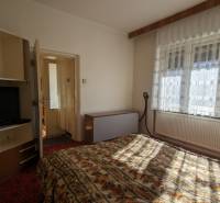 5-izbový rodinný dom na predaj v Hornom Ohaji, okr. NR, pozemok 1251m2 - Spálňa v rodinnom dome s televízorom a kvetinovým vzorom posteľnej bielizne.