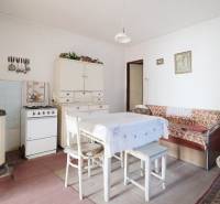 Menší rodinný dom len pár metrov od centra mesta Rajec - Jedáleň s plynovým sporákom, stolom a pohovkou v rodinnom dome, podlaha s dreveným dekorom.