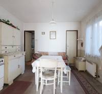 Menší rodinný dom len pár metrov od centra mesta Rajec - Kuchyňa v rodinnom dome s retro nábytkom, stolom a umývadlom, podlaha s dreveným dekorom.