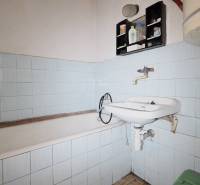 Menší rodinný dom len pár metrov od centra mesta Rajec - Kúpeľňa s vaňou, umývadlom a modrými obkladačkami v rodinnom dome.